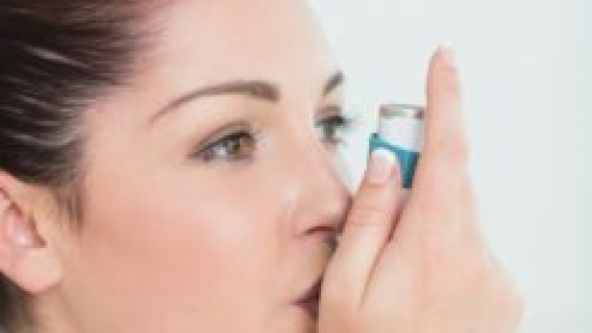 Woman with asthma using a blue inhaler