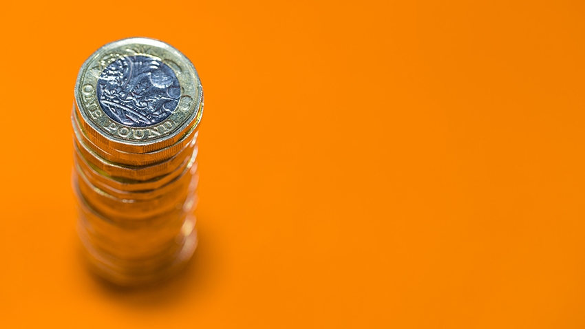 Stack of pound coins against orange background