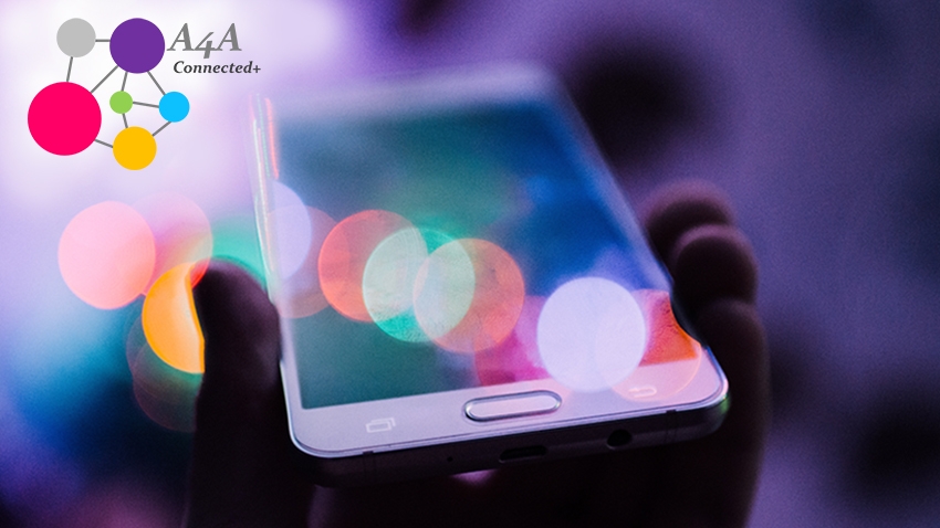 Hand holding mobile phone with light reflecting off it with A4A Connected Plus logo